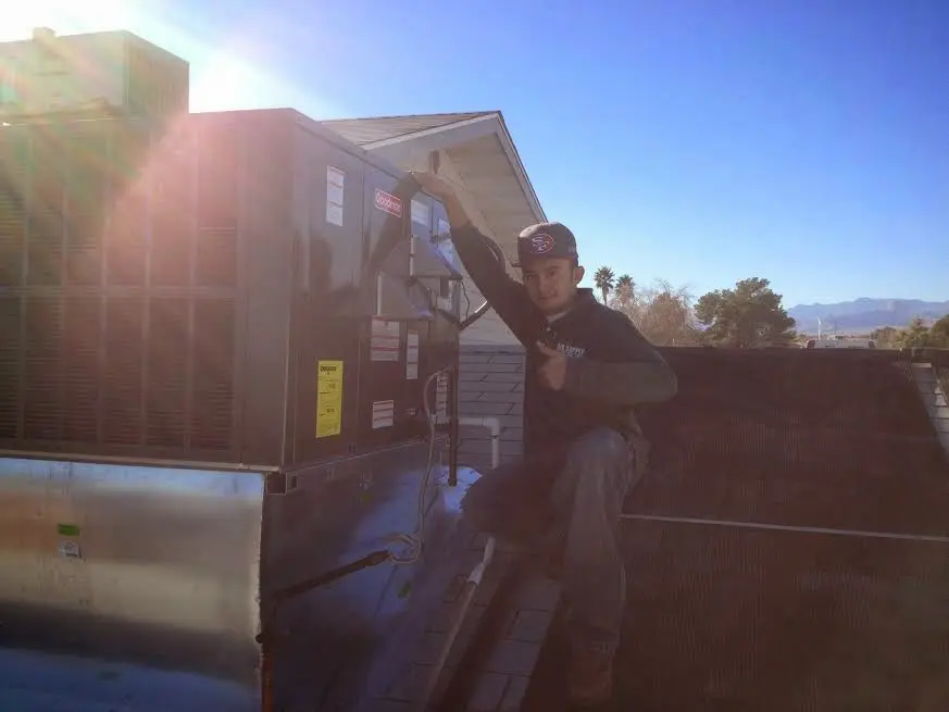 HVAC technician performing AC Tune-Up on a rooftop unit in Brown Deer
